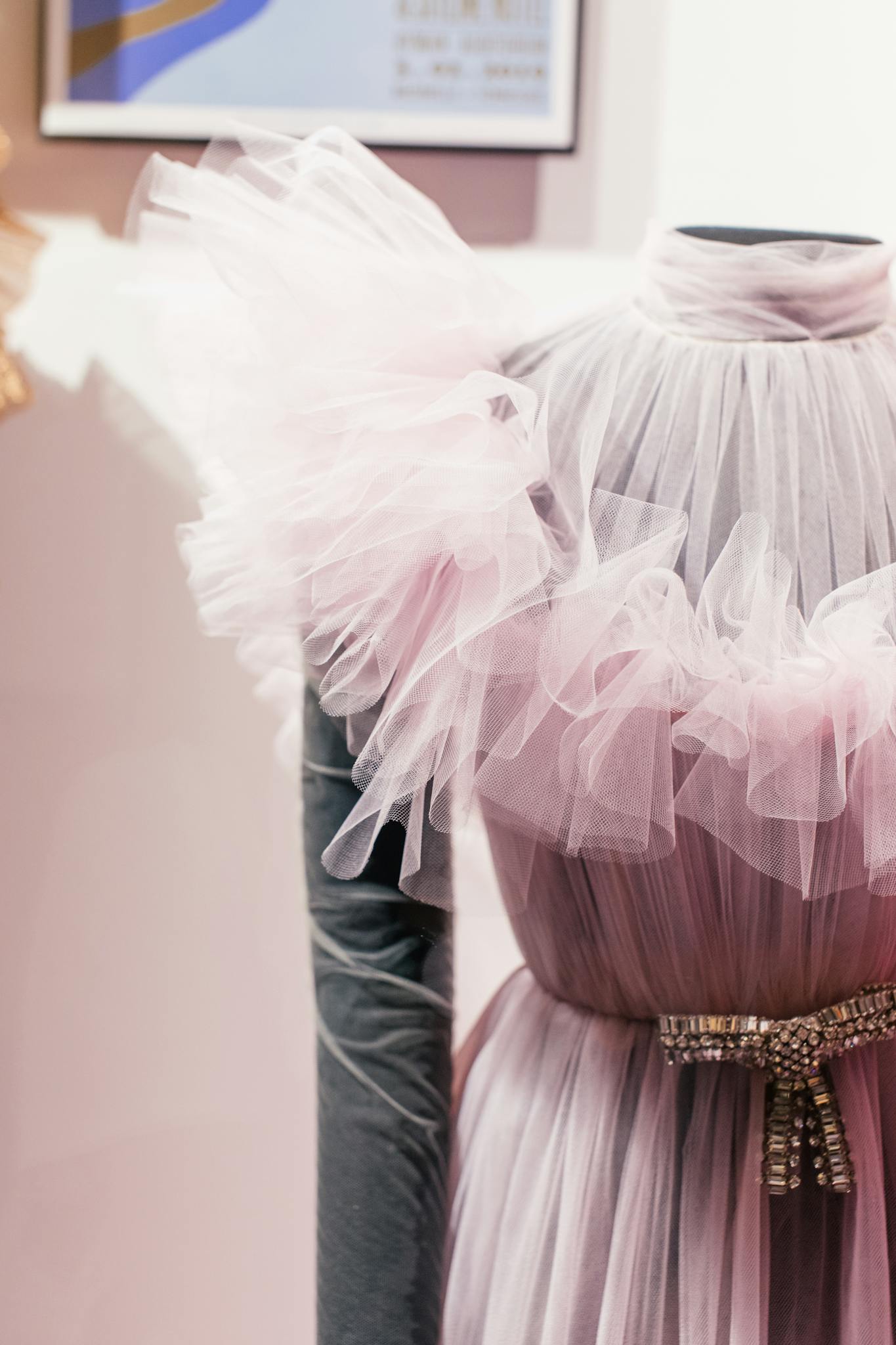 A stylish pink sheer gown with ruffled fabric showcased in a fashion studio, highlighting elegance and design.